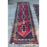 Eastern runner with blood red field and repeat cruciform medallions in border, 316cm x 77cm,