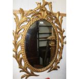 George III carved giltwood wall mirror with oval plate in ropetwist and c-scroll frame with