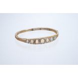 Victorian style opal and diamond hinged bangle with seven oval cabochon opals interspersed by