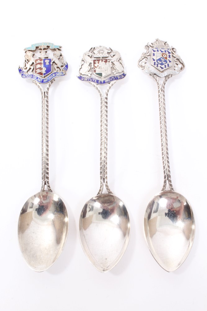 Three Edwardian silver and enamelled souvenir spoons with pierced coats of arms terminals for