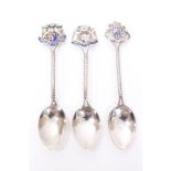 Three Edwardian silver and enamelled souvenir spoons with pierced coats of arms terminals for