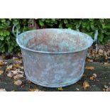 Large copper vessel of cylindrical form with domed base and twin loop handles,