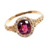 Almandine garnet and diamond cluster ring with an oval mixed cut garnet surrounded by a border of
