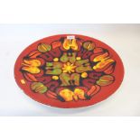 Poole Delphis circular charger with abstract floral decoration on red, orange,