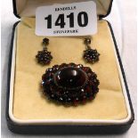 A later boxed part suite of garnet set jewellery, comprising cabochon brooch and pair of drop