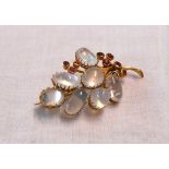 A 2" yellow metal bunch of grapes pattern brooch, set with seven cabochon moonstones and nine