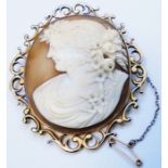 A 2 1/2" ornate yellow metal framed oval cameo brooch with pierced border and safety chain