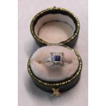 An early 20th Century 18ct. gold and platinum square panel ring, set with central sapphire and