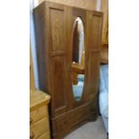 An Edwardian inlaid mahogany single wardrobe with bevelled oval mirror panel door and drawer under -