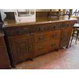 A 5' 8" Edwardian polished oak sideboard with low raised back, three carved frieze drawers, two