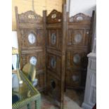 An eastern stained and pierced wood four fold dressing screen with wrought iron floral inset