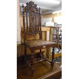 A 19th Century carved and pierced oak baronial style high back hall chair with solid seat and turned
