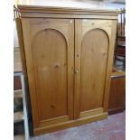 A 4' antique stripped pine linen cupboard with five shelves enclosed by a pair of arched panel