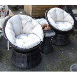 A pair of woven plastic garden swivel tub chairs with fitted cushions - sold with a matching table