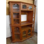 A 5' 4" eastern hardwood two part wall cabinet with an array of glazed panel doors, canted sides and