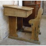 An early 20th Century oak lift-top school desk with original inkwell and integral seat, set on