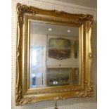 A reproduction ornate gilt framed bevelled wall mirror