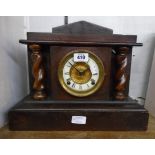 A late 19th Century American stained wood cased mantel clock with flanking barley twist columns,