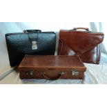 A brown leather attaché case and two briefcases