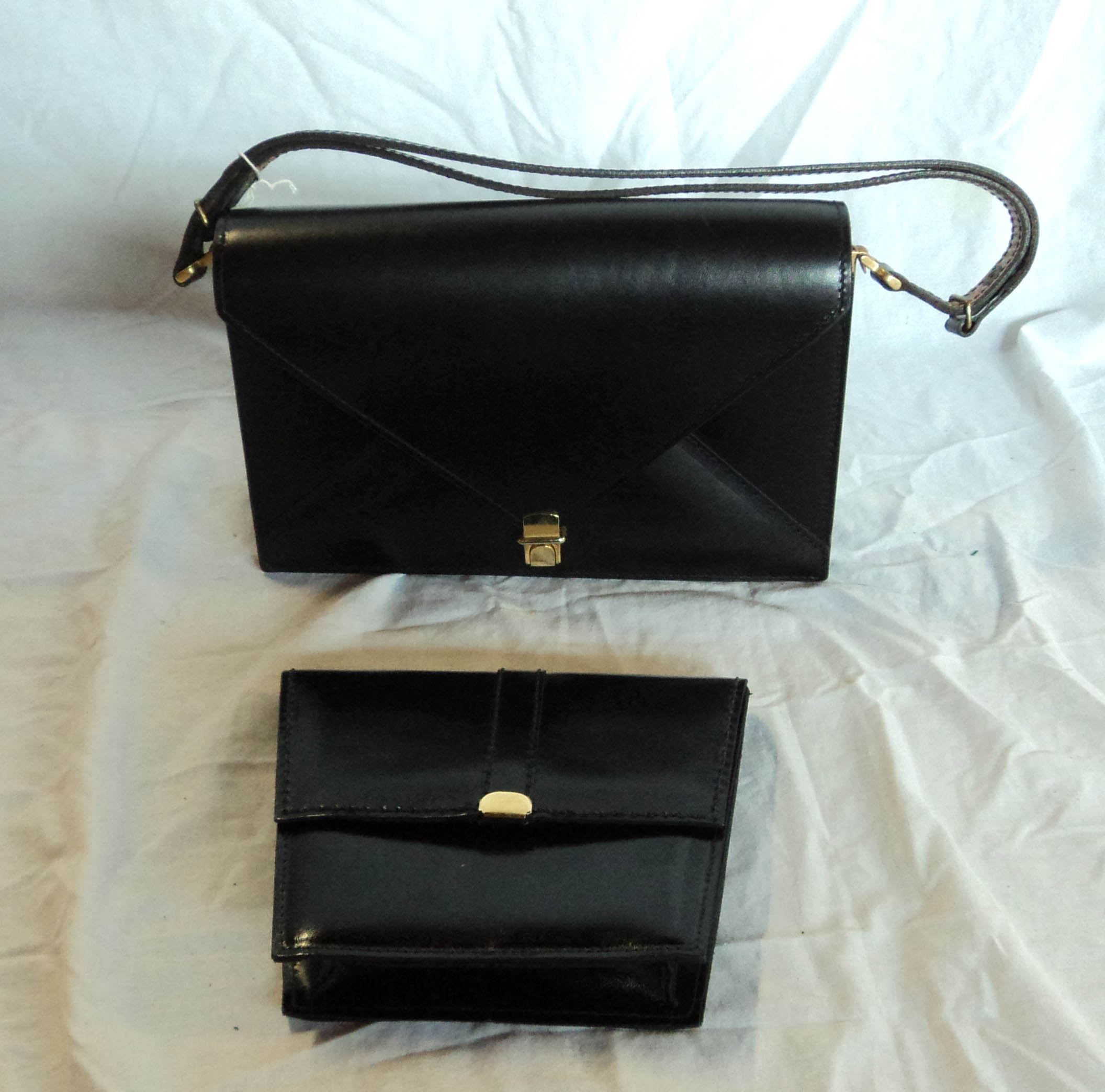 A black leather handbag and similar clutch