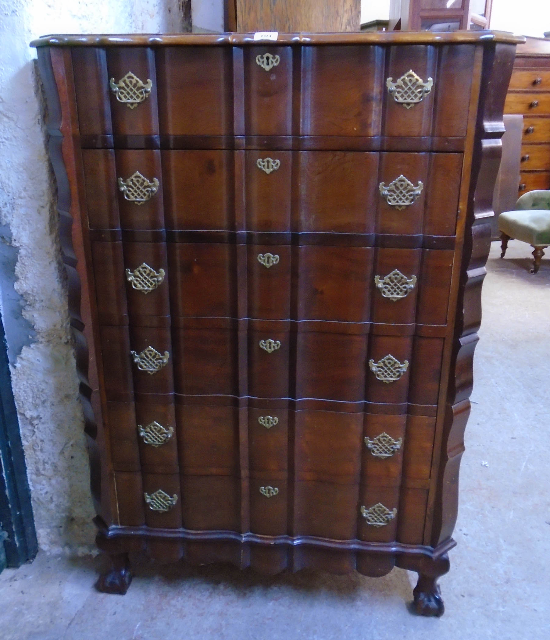 A 34 1/2" polished hardwood serpentine front chest in the antique style with six long drawers and