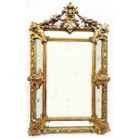 An antique German ornate gilt gesso framed wall mirror with mask and fruit swag pediment, star cut