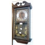 A modern polished wood cased wall clock with visible pendulum and gong striking movement