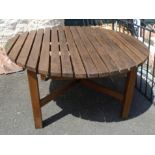 A 4' 11" diameter slatted teak garden table set on standard supports and cross stretcher base