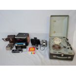 A reel-to-reel tape deck, a Polaroid camera, a Bell and Howell 624 film camera and two other