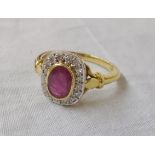 An 18ct. gold ring, set with central collar set oval ruby within a diamond encrusted border