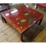 A 36" modern Oriental red lacquered and highly decorated coffee table with glass top, set on