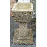 A concrete square planter, set on stepped pedestal base