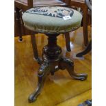 A Victorian carved walnut adjustable piano stool with tapestry upholstered circular seat panel and