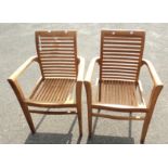 A pair of teak elbow chairs with slatted backs and seats