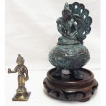 An oriental metal oil burner with Shiva seated on lid set on a wooden base - sold with a small brass