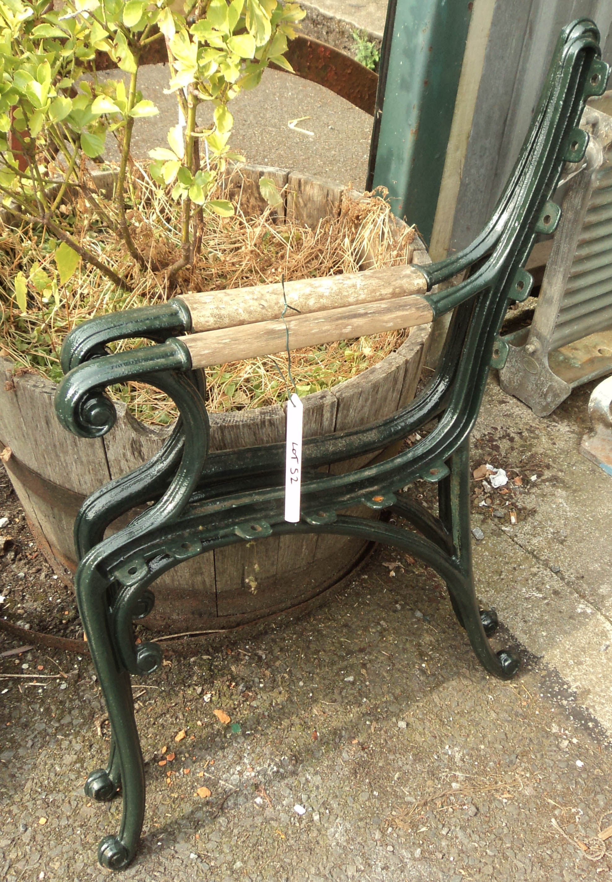 A pair of painted cast iron bench ends with wood inset armrests