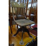 An early 20th Century stained oak framed swivel office chair with shaped stick back and rexine