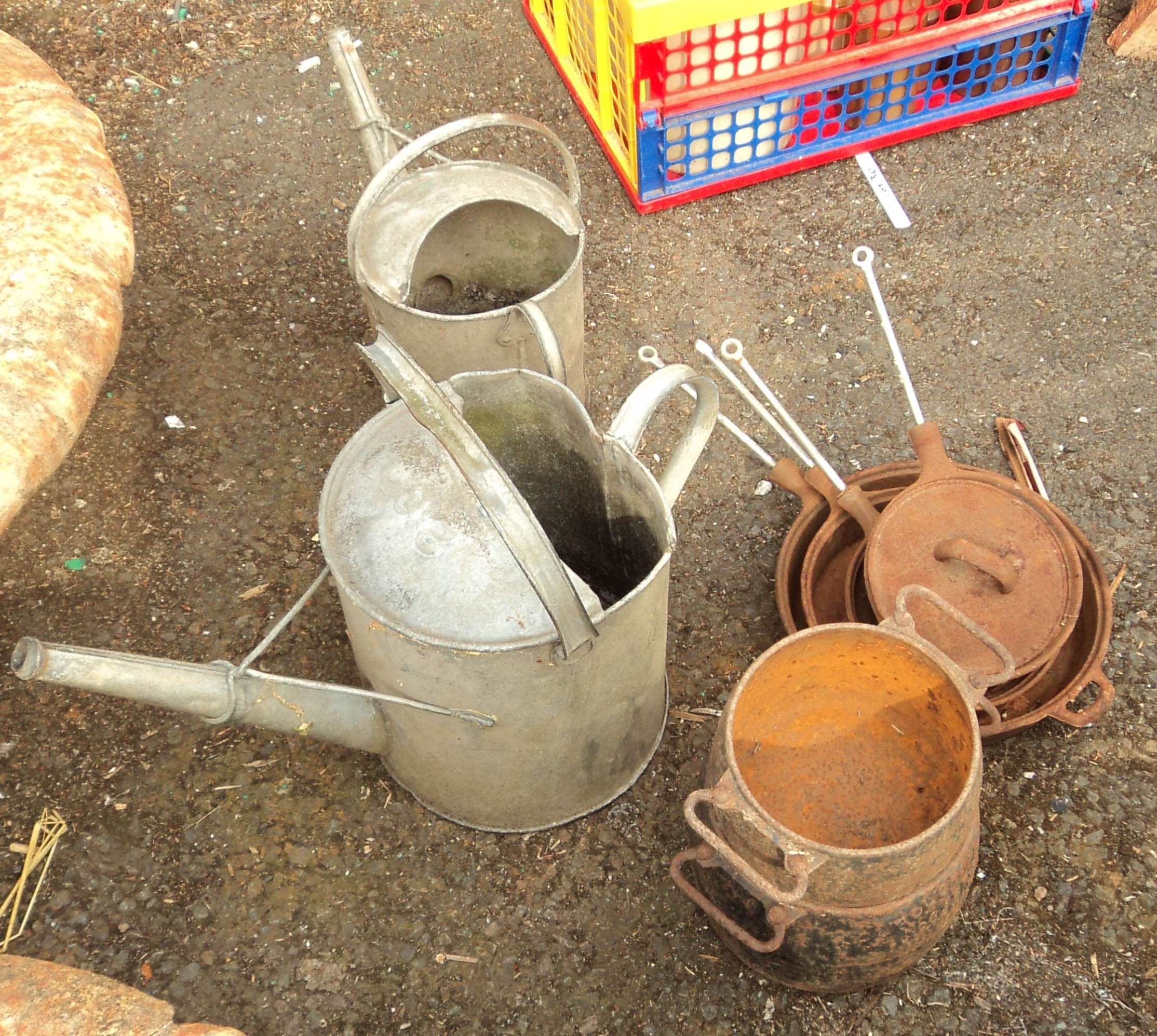 Two galvanised watering cans, three cast iron pans and two two handled pots