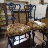 A set of four late Victorian ebonised framed dining chairs with ornate pierced splat backs and