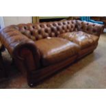 A 7' modern brown button back leather Chesterfield settee, set on polished wood turned front legs