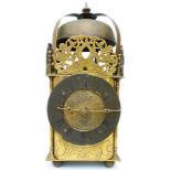 A 12 3/4" antique brass lantern clock with pierced brass dolphin decorated panels surrounding bell