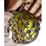 A large green glass fishing float in net - diameter 13"