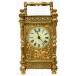 An ornate brass and bevelled glass cased carriage timepiece with gilt metal border to dial and eight