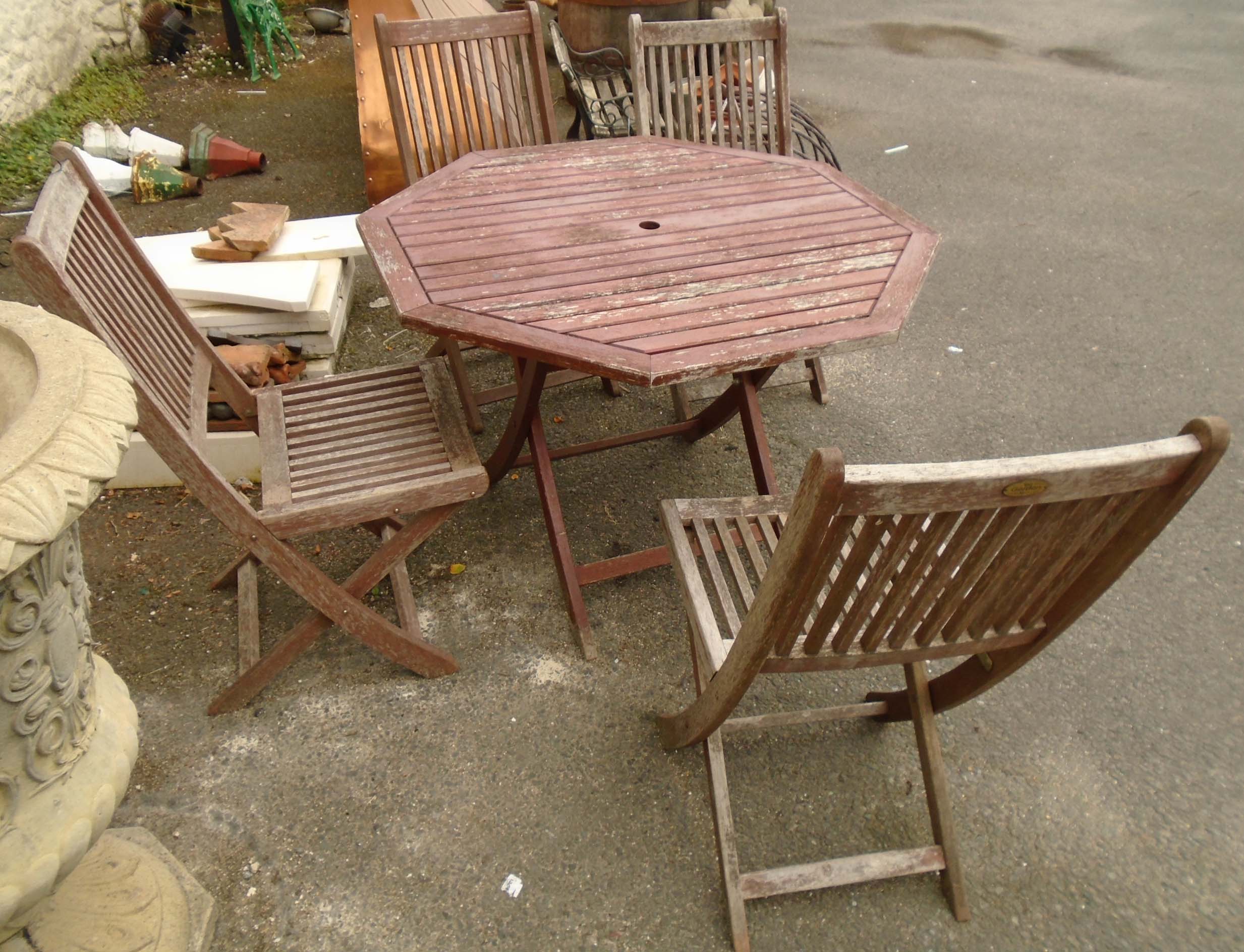 A set of four stained and slatted teak folding chairs - sold with an octagonal table to match