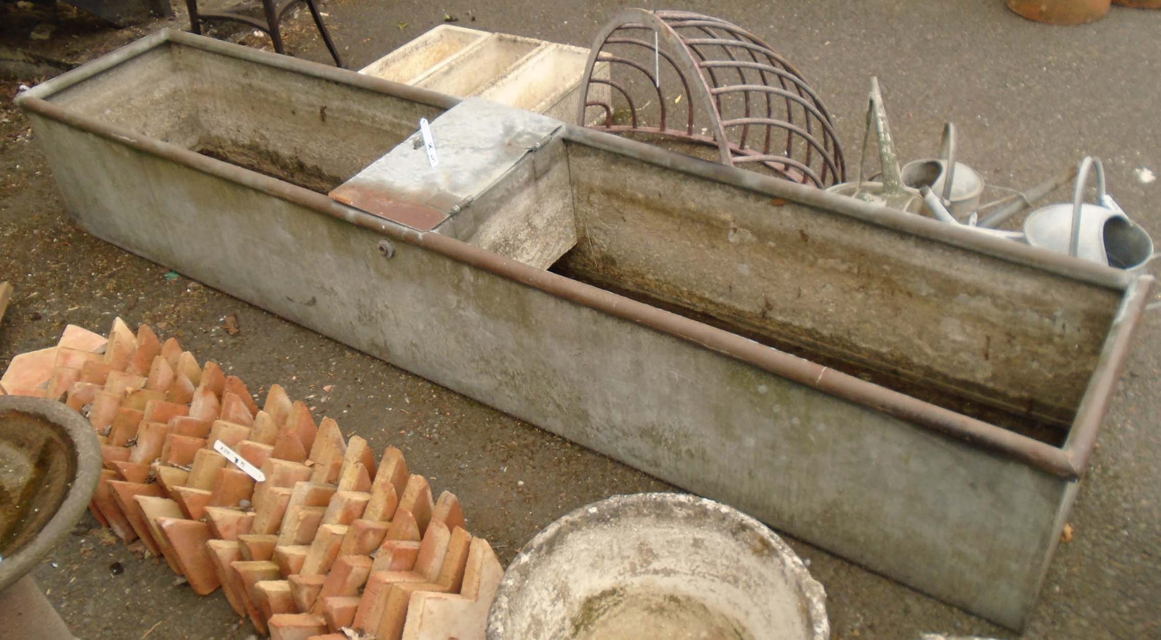 A galvanized water trough with central ball cock housing - length 8'