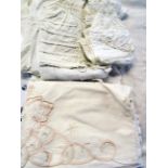 A bag of linen including a christening gown, baby clothes, bonnets, etc.