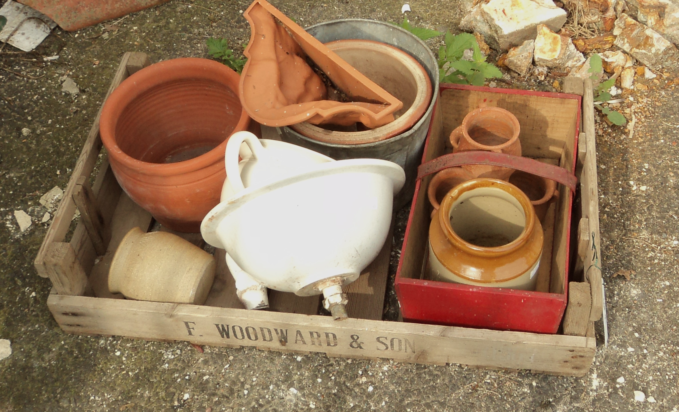 A chitting tray containing various terracotta plant pots, trug, wall pocket, etc.