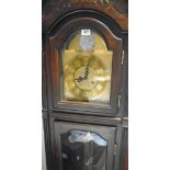 A reproduction mahogany longcase clock with decorative dial, glazed door, visible pendulum and
