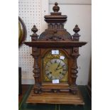 A late 19th Century German stained walnut cased ornate mantel clock with turned finials, flanking