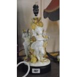 A figural table lamp featuring musical cherubs around a tree trunk